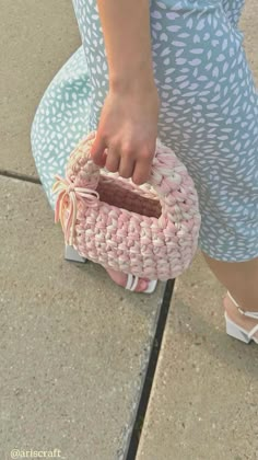 a close up of a person's hand holding a small purse on the ground