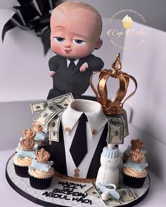 a baby in a suit and tie on top of a cake with cupcakes