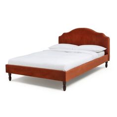 a bed that is made up with white sheets and brown headboard on top of it