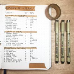 an open planner with three markers and some pencils