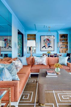 a living room with blue walls and orange couches in the center, along with other furniture