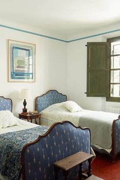 two beds in a bedroom with blue and white bedding