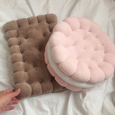 a person is laying on a bed with two pillows and a pillow in the shape of a cushion