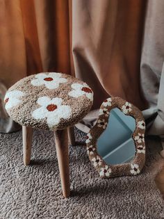 two small stools with flowers on them are sitting next to a mirror and curtain