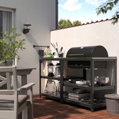 an outdoor bbq grill with pots and pans on the outside patio, next to a table