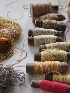 several spools of thread are lined up on a table with twine in them