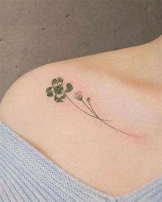 a four leaf clover tattoo on the left side of the shoulder, with three leaves attached to it