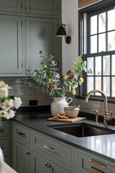 a vase with flowers in it sitting on a kitchen counter next to a sink and window