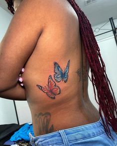 a woman's back with two butterflies tattooed on her left side ribcage