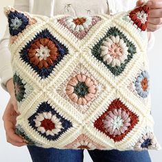 a woman is holding a crocheted pillow in her hands