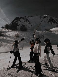 five skiers are standing on the snow with their ski poles up in the air