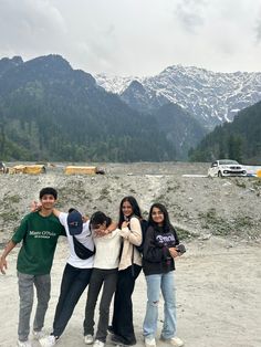 four young people posing for a photo in front of mountains and snow - capped peaks