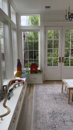 a room filled with lots of windows and toys on top of a rug next to a table