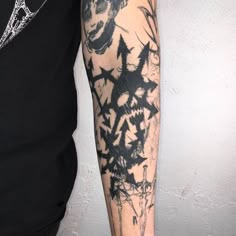 a man's arm with black ink and tattoos on it, next to a white wall