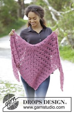 a woman is holding up a pink shawl