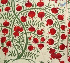 an intricately designed wall hanging with red flowers and leaves on white fabric, in the shape of a tree