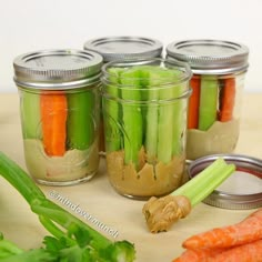 carrots and celery in mason jars on a table with other vegetables around them