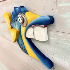 a blue and yellow fish head mounted to the side of a wooden wall