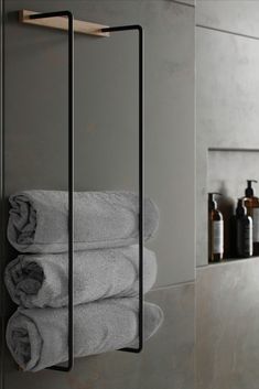 two towels are hanging on the wall in front of a towel rack with three folded gray towels