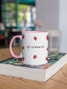 a pink and white coffee mug sitting on top of a book