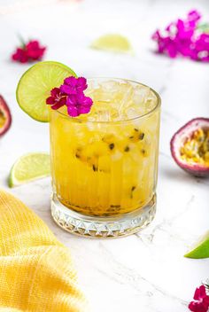 an alcoholic cocktail in a glass with lime and flower garnish