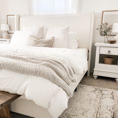 a bed with white linens and pillows in a bedroom next to a window,