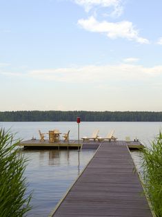 there is a dock that leads to the water and two lawn chairs are on it