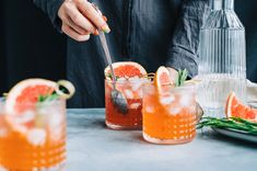 the bartender is making a drink with grapefruit and mint