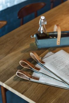 three pairs of scissors sitting on top of a wooden table next to a bottle of wine