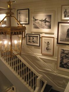 a stairway with pictures on the wall and chandelier hanging from it's handrail