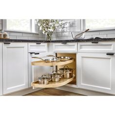 an open kitchen cabinet with pots and pans