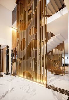 an artisticly designed stair case in a modern house with marble floors and walls, along with gold accents