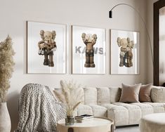 a living room filled with white furniture and pictures on the wall above it's coffee table