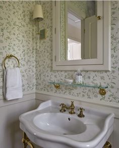 a white sink sitting under a bathroom mirror next to a wall mounted faucet