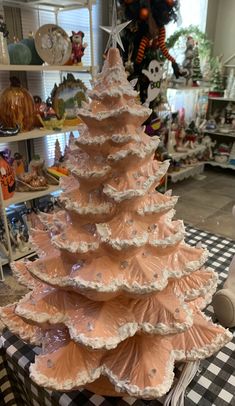 a christmas tree is sitting on a checkered tablecloth in a store with other holiday decorations