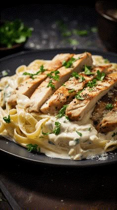 a plate of chicken alfredo with parsley on top