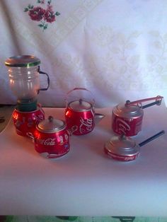 coca - cola canisters are lined up on a table with tea kettles