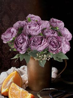 purple roses and oranges in a copper vase