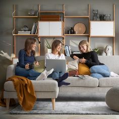 two women sitting on a couch using laptops