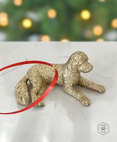 a golden toy dog laying on its side with a red ribbon around it's neck