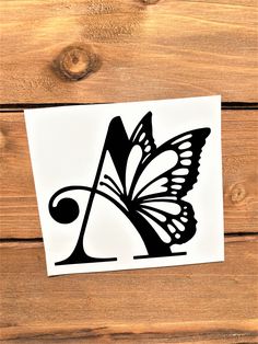 a piece of paper with a black and white butterfly on it, next to a wooden background