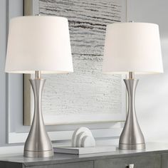 two lamps sitting on top of a table next to a mirror