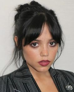 a close up of a person wearing a suit and tie with hair in a bun