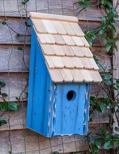 a blue birdhouse hanging on the side of a wooden fence