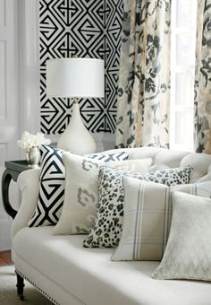 a living room filled with lots of white furniture and pillows on top of a couch