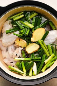 a pot filled with chicken, green beans and other vegetables on top of a table