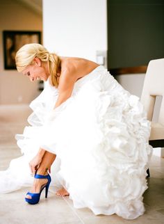 a woman in a white dress kneeling down on the floor with her foot up and wearing high heels