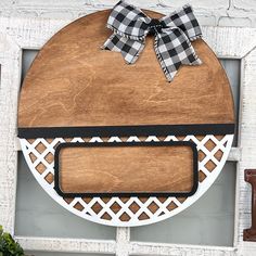 a wooden sign hanging on the side of a white brick wall with a black and white checkered bow