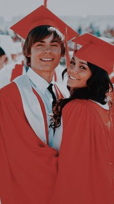 a man and woman in graduation caps and gowns hugging each other at the same time