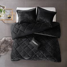 a bed with black comforters and pillows